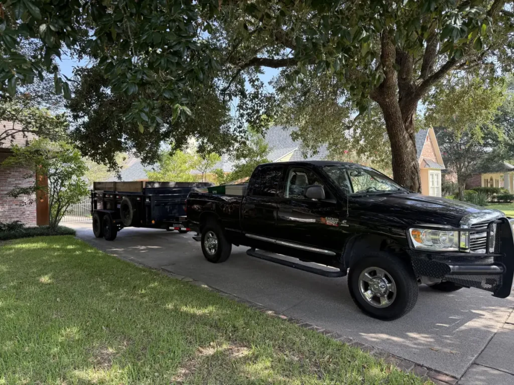Acadian Services truck and dump trailer parked in a residential driveway in Denham Springs, Louisiana, ready for a junk removal job.