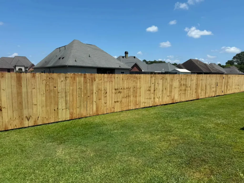 A finished six-foot wood privacy fence running along a back yard property line in Denham Springs, Louisiana.
